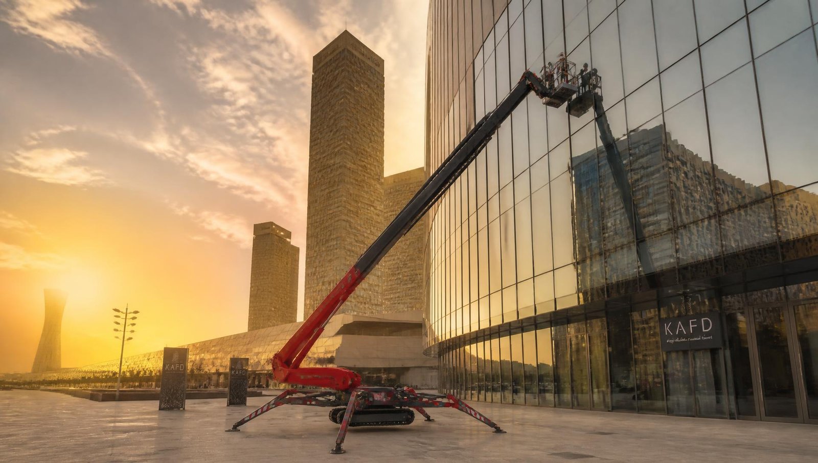 Tracked aerial work platform positioned on outriggers beside a glass tower at KAFD in Riyadh